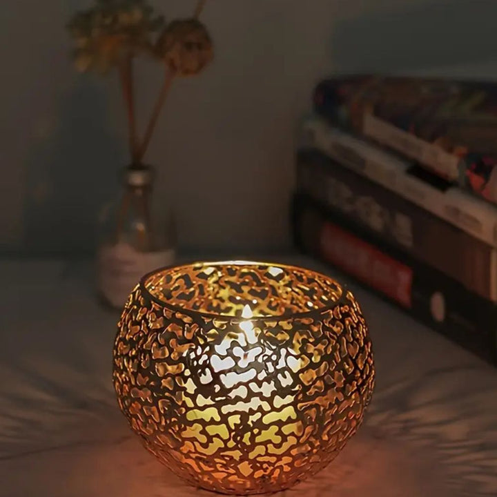 Gold geometric iron tealight holder with a sphere design, casting intricate shadows.