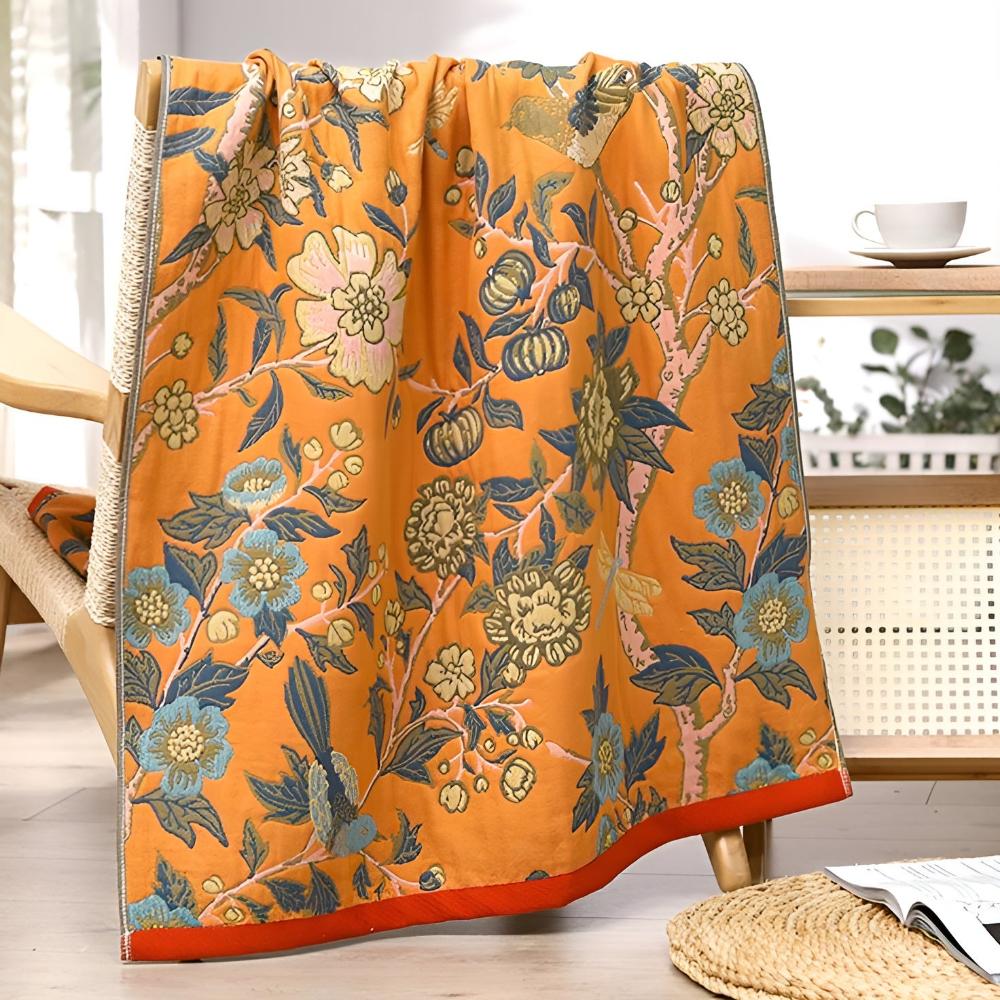 An orange cotton bath towel featuring a blue and yellow floral hibiscus pattern.