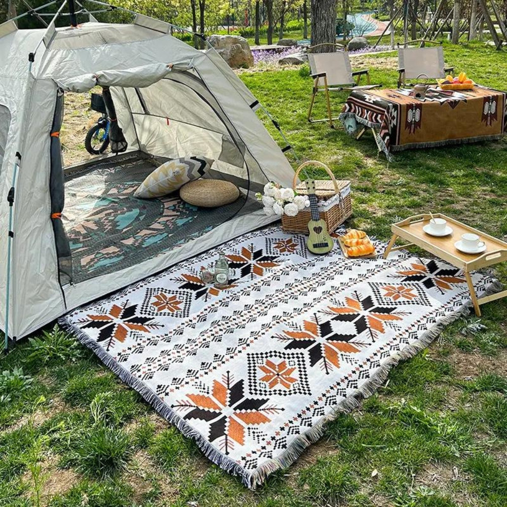 Moroccan Boho picnic mat with geometric patterns laid out on grass next to a tent.