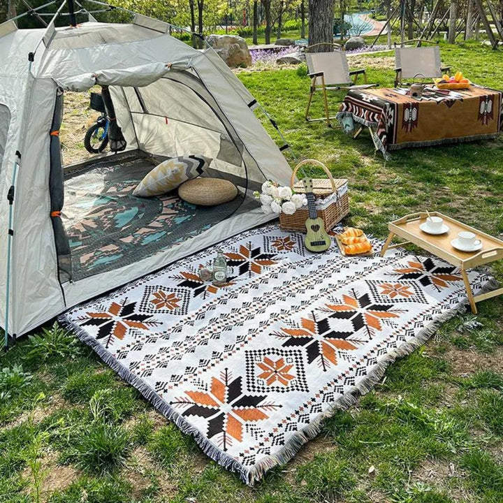 Moroccan Boho picnic mat with geometric patterns laid out on grass next to a tent.