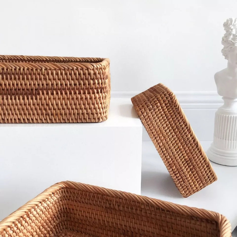 Three hand-woven rattan storage baskets in natural tones on white surfaces.