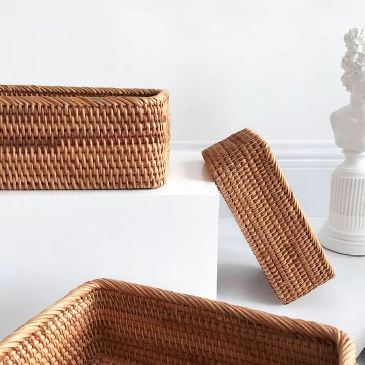 Three hand-woven rattan storage baskets in natural tones on white surfaces.