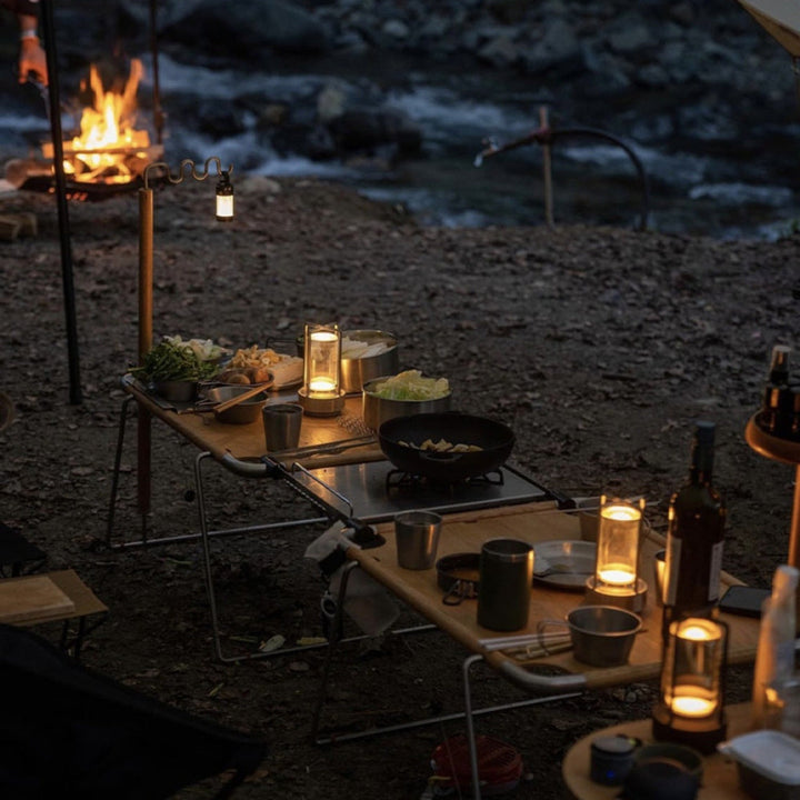 Crystal table lantern with warm ambient glow on a table at a campsite.