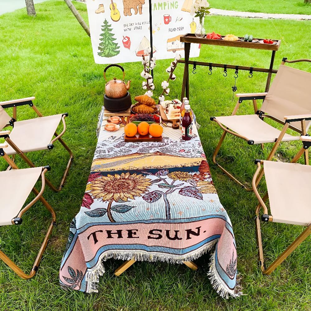 Boho style tapestry throw with a sun design, draped over a picnic table with chairs.