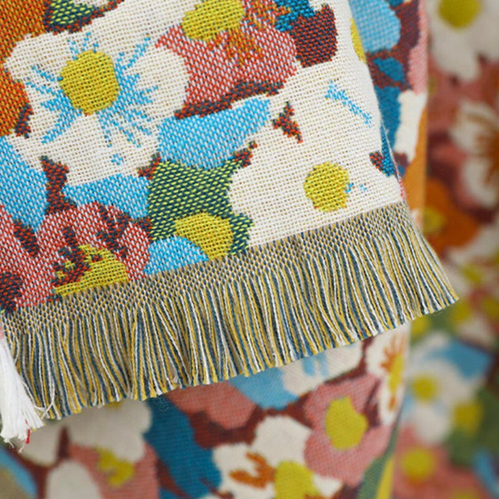 A close-up of a reversible cotton bath towel with a vibrant floral pattern and fringed edges.