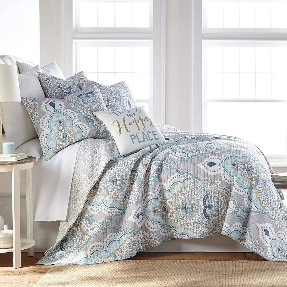 Paisley aqua teal coverlet set with decorative pillows on a bed.