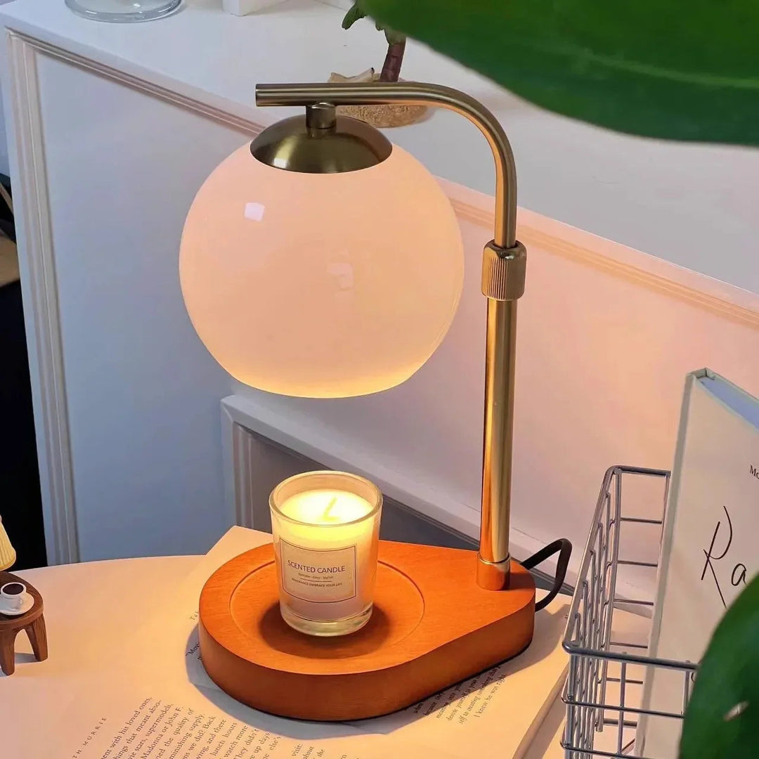 Sculpted glass candle warmer lamp with a wooden base and a lit candle.