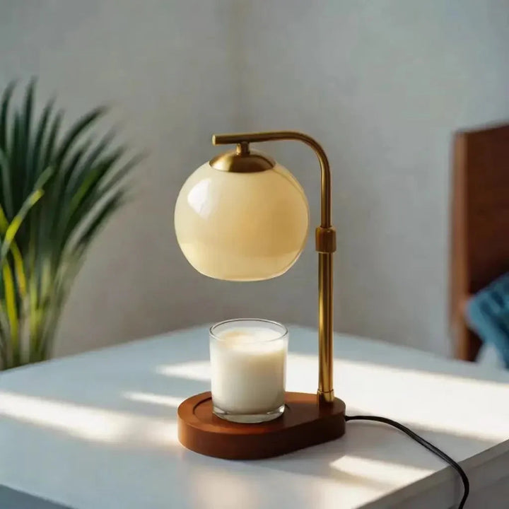 Sculpted glass candle warmer lamp with a retro amber shade and a warm glow, placed on a wooden base next to a candle.