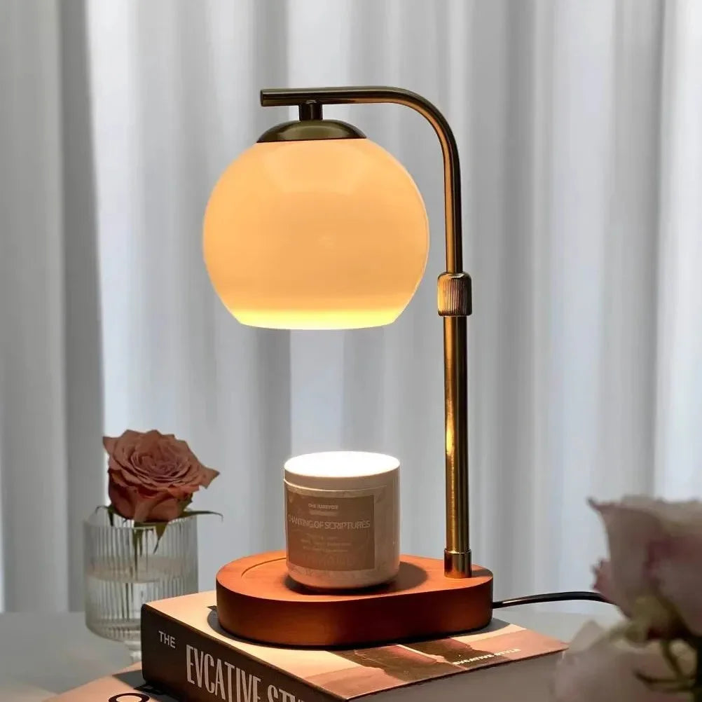 Sculpted glass candle warmer lamp with a retro amber glow, placed on a book next to a rose.