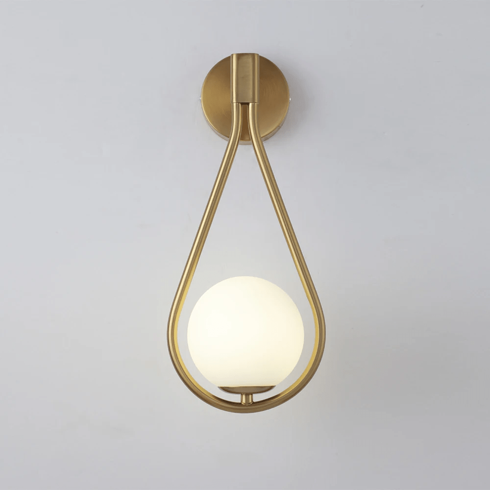 Brushed brass teardrop wall sconce with a frosted glass globe light