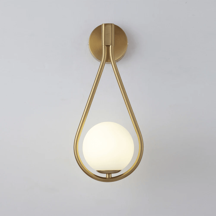 Brushed brass teardrop wall sconce with a frosted glass globe light