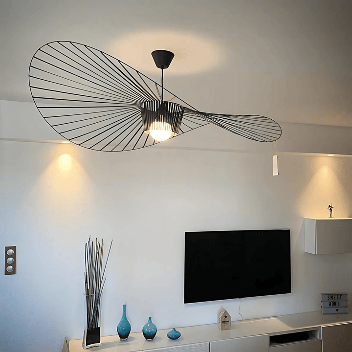 Black contemporary pendant light with a unique wave design, illuminating a living room.