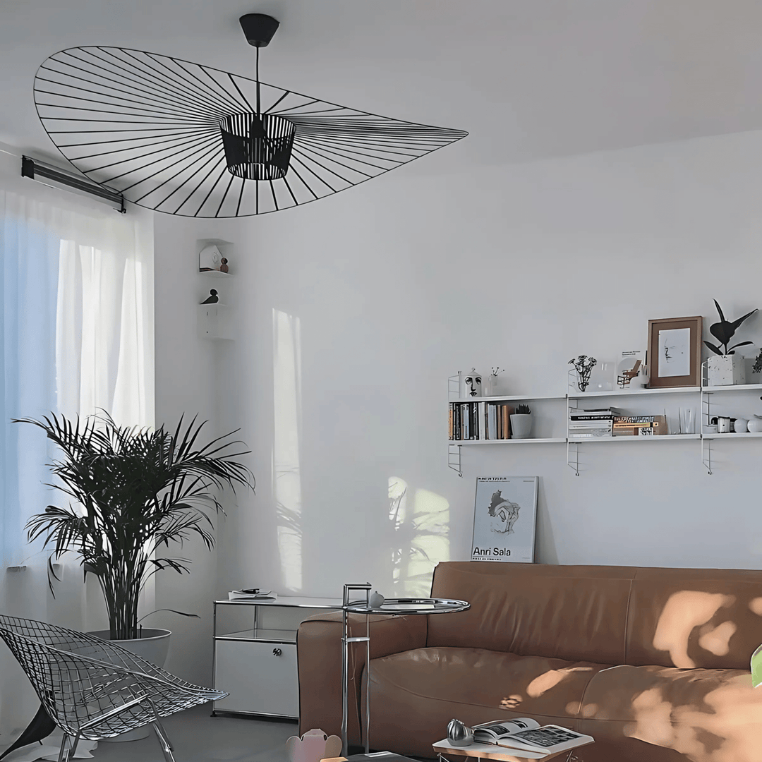 Contemporary pendant light with a black wire frame resembling a fan, hanging above a living room.