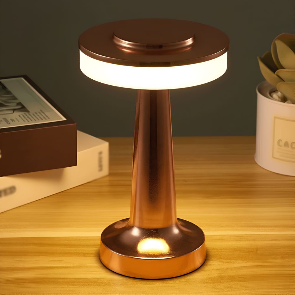 Copper cordless table lamp with a warm ambient glow, sitting on a wooden surface.
