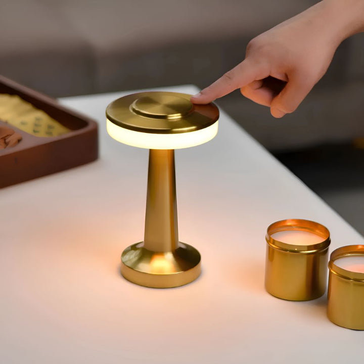 A hand touches the top of a gold Dome Cordless Table Lamp, illuminating it with warm ambient light.