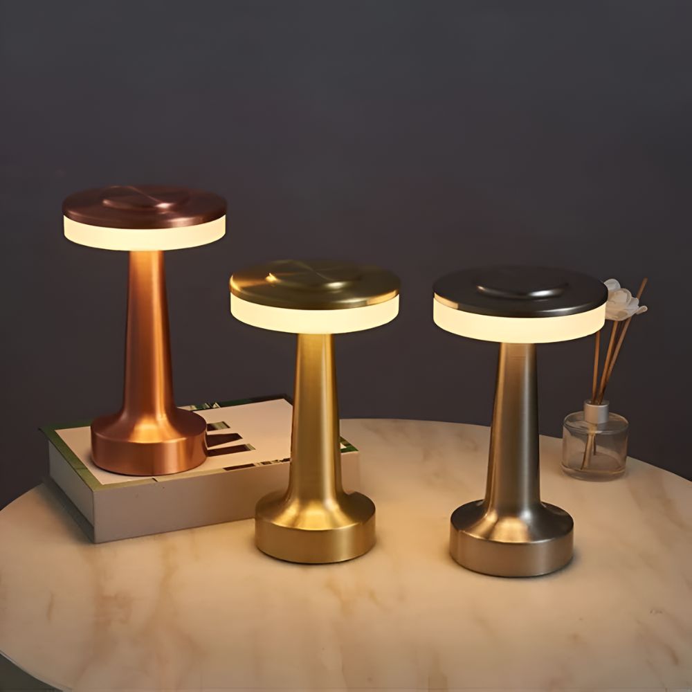 Three Dome Cordless Table Lamps in copper, gold, and silver finishes on a marble table.