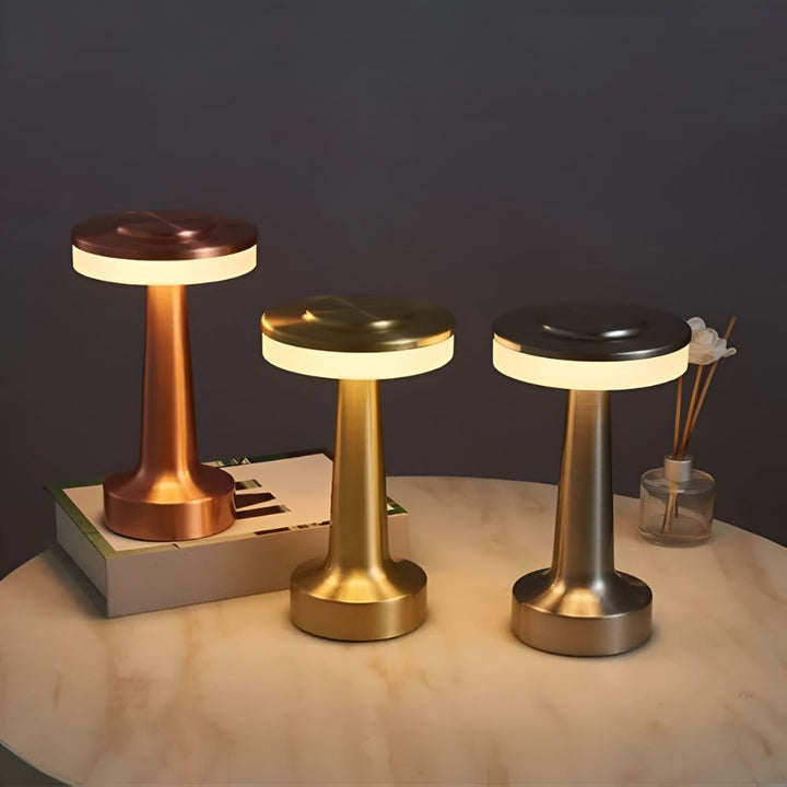 Three Dome Cordless Table Lamps in copper, gold, and silver finishes on a marble table.