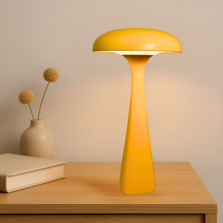 Yellow jellyfish-shaped desk lamp with a soft ambient glow on a wooden table.