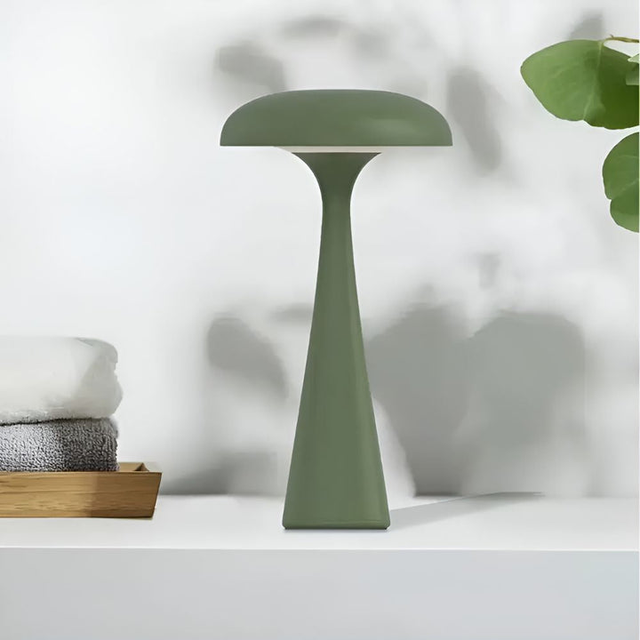 Green Jellyfish Desk Lamp with a soft ambient glow on a white shelf.