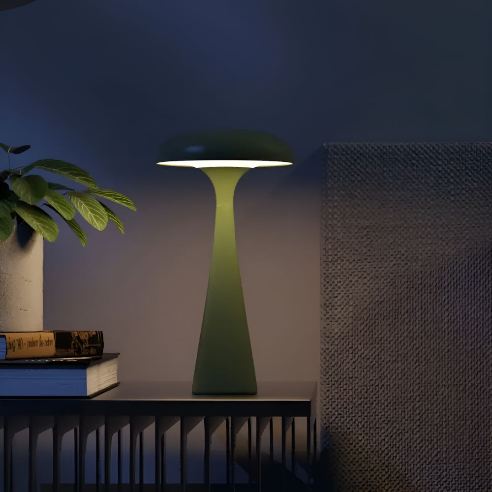 Green Jellyfish Desk Lamp with a soft ambient glow on a shelf with books and a plant.