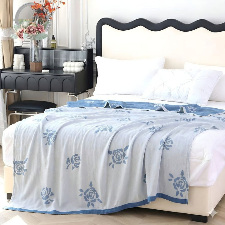 Light blue bamboo fiber cooling blanket with a rose pattern draped on a bed.