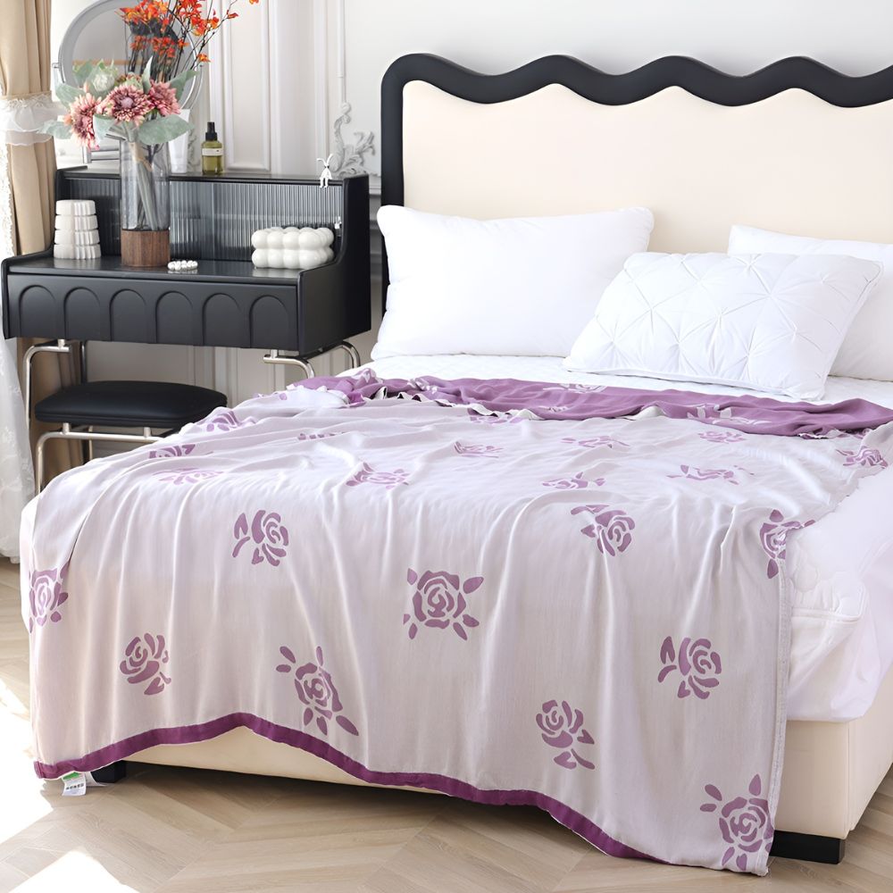 Lightweight bamboo fiber cooling blanket with purple rose pattern draped on a bed.
