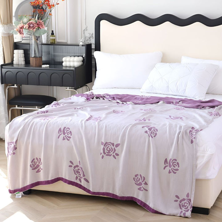 Lightweight bamboo fiber cooling blanket with purple rose pattern draped on a bed.