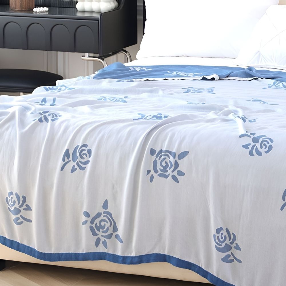 White bamboo fiber cooling blanket with blue rose pattern and a blue border.