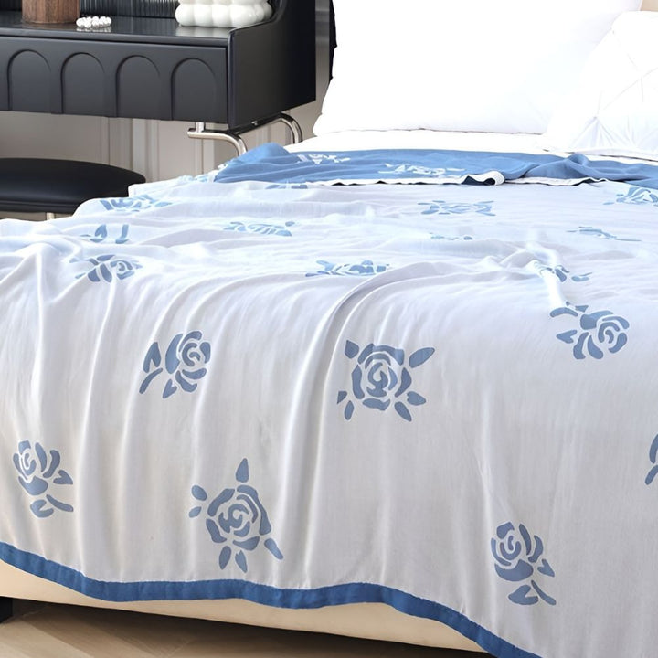 White bamboo fiber cooling blanket with blue rose pattern and a blue border.