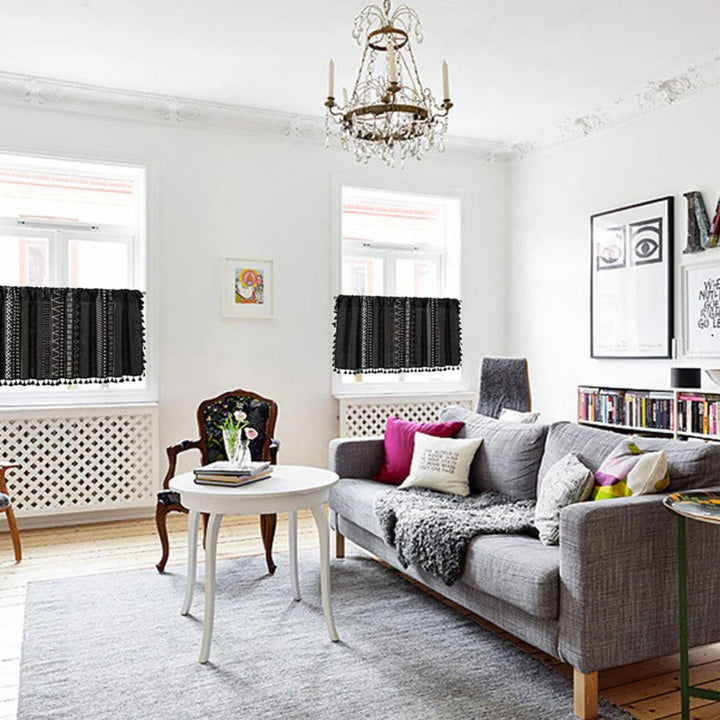 Black geometric tribal tassel cabinet curtain with white patterns and tassels, shown on a small window.