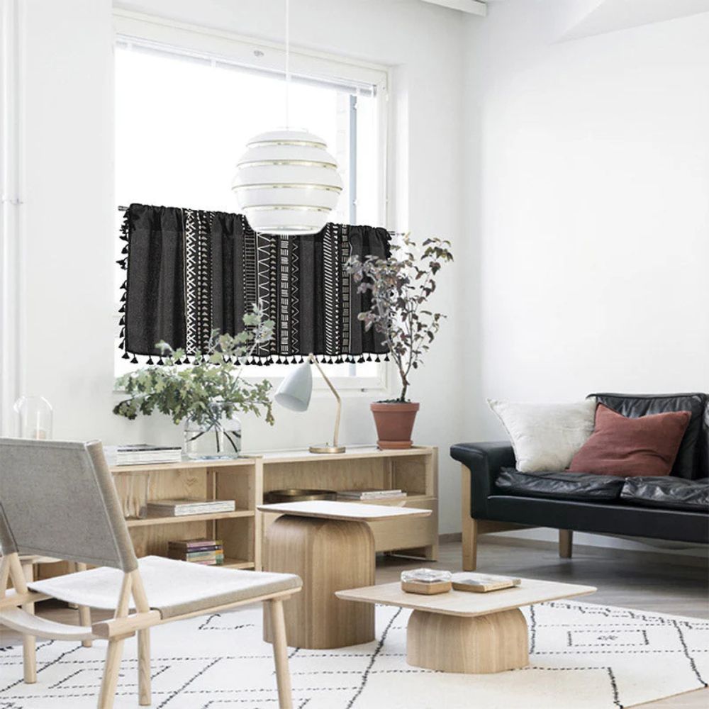 Black geometric tribal tassel cabinet curtain with white patterns, hanging on a window.