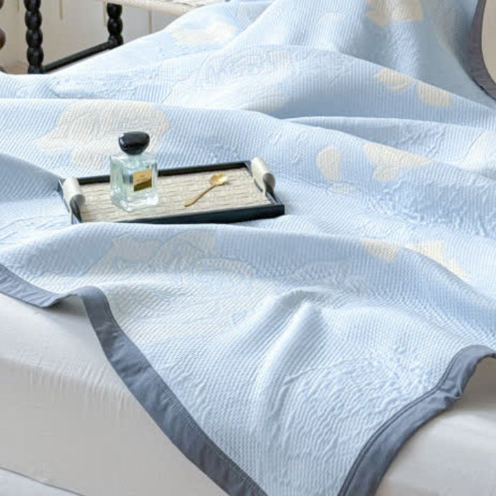 Blue Rose Bloom Cotton Blanket with a decorative pattern and a grey border, shown on a bed with a perfume bottle and tray.