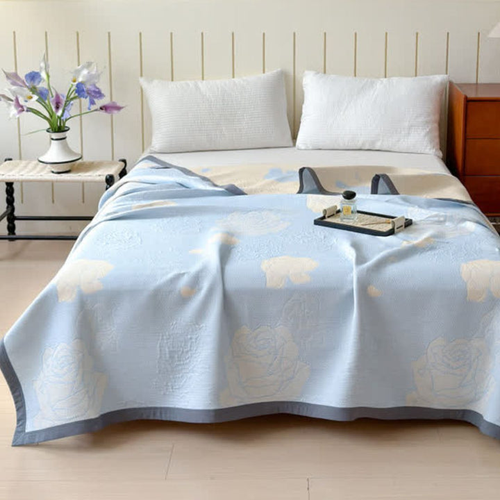 Blue Rose Bloom Cotton Blanket with a rose pattern, draped over a bed with two pillows and a tray.