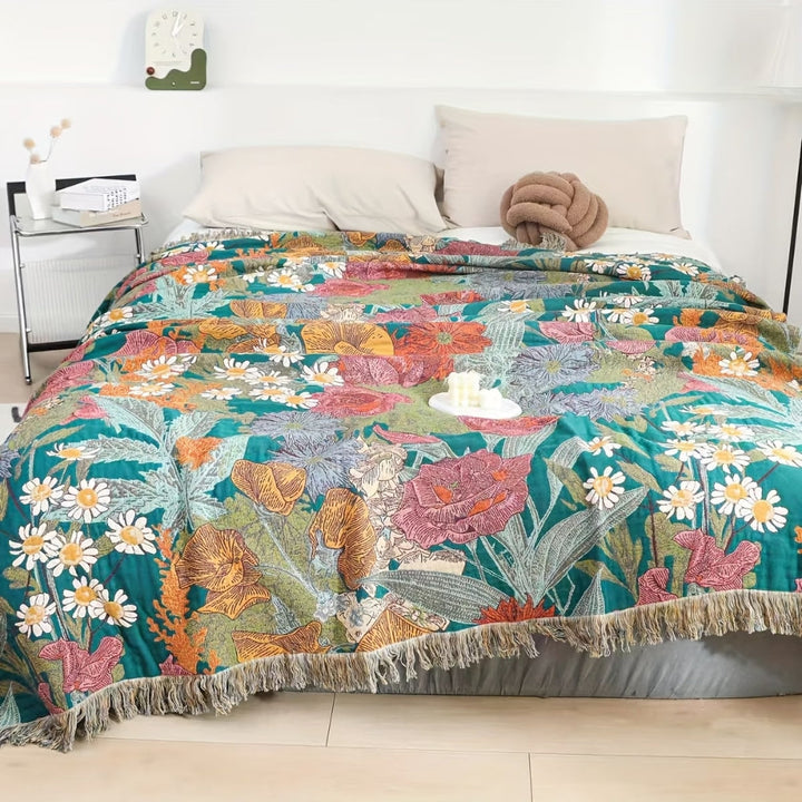 Bohemian floral patchwork tassel blanket with fringe detail on a bed.