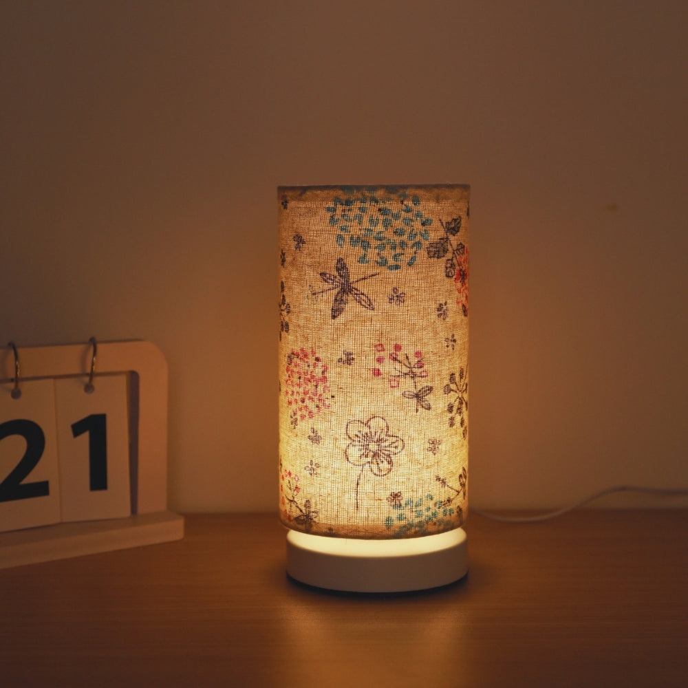 Botanical floral fabric table lamp with a warm ambient glow, next to a wooden calendar showing the 21st.