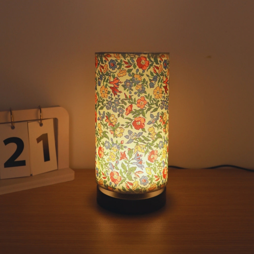 Botanical floral fabric table lamp with a warm ambient glow, next to a desk calendar showing the 21st.