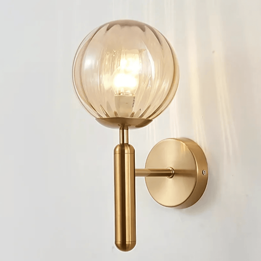 Brass metal wall sconce with a fluted amber glass globe and a dimmable bulb.
