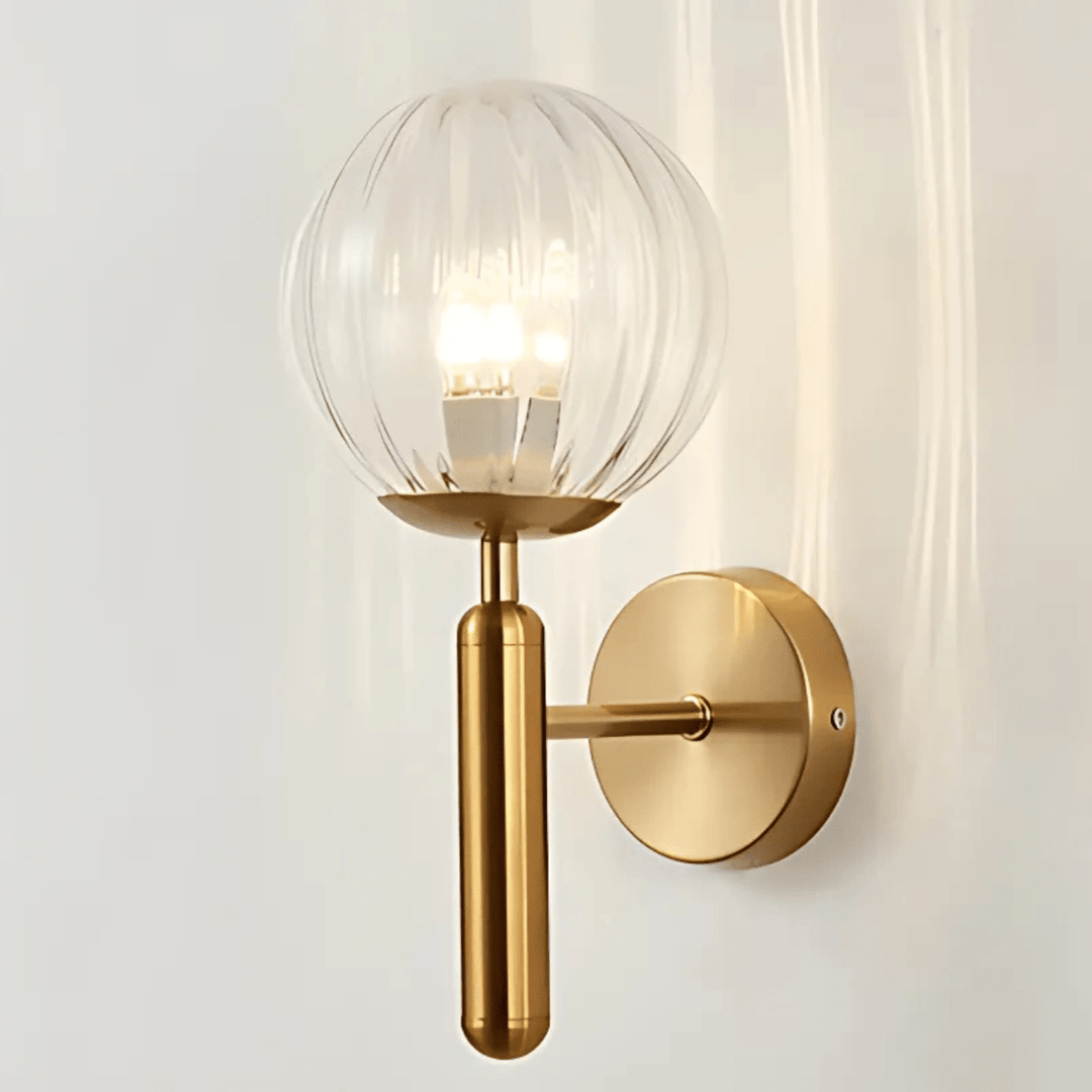 Brass metal wall sconce with a ribbed glass globe and a dimmable light.