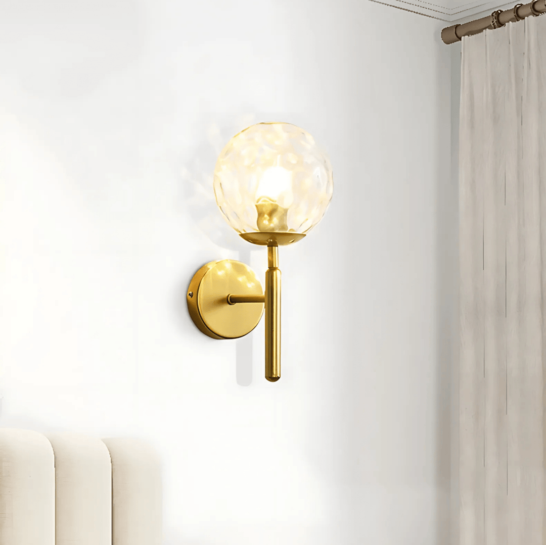 Brass metal wall sconce with a textured glass globe and a dimmable feature.