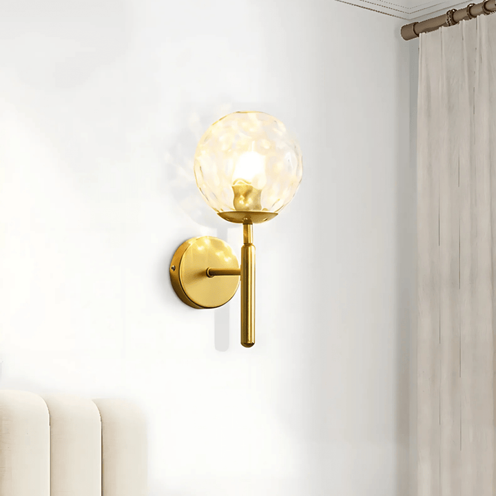 Brass metal wall sconce with a textured glass globe and a dimmable feature.
