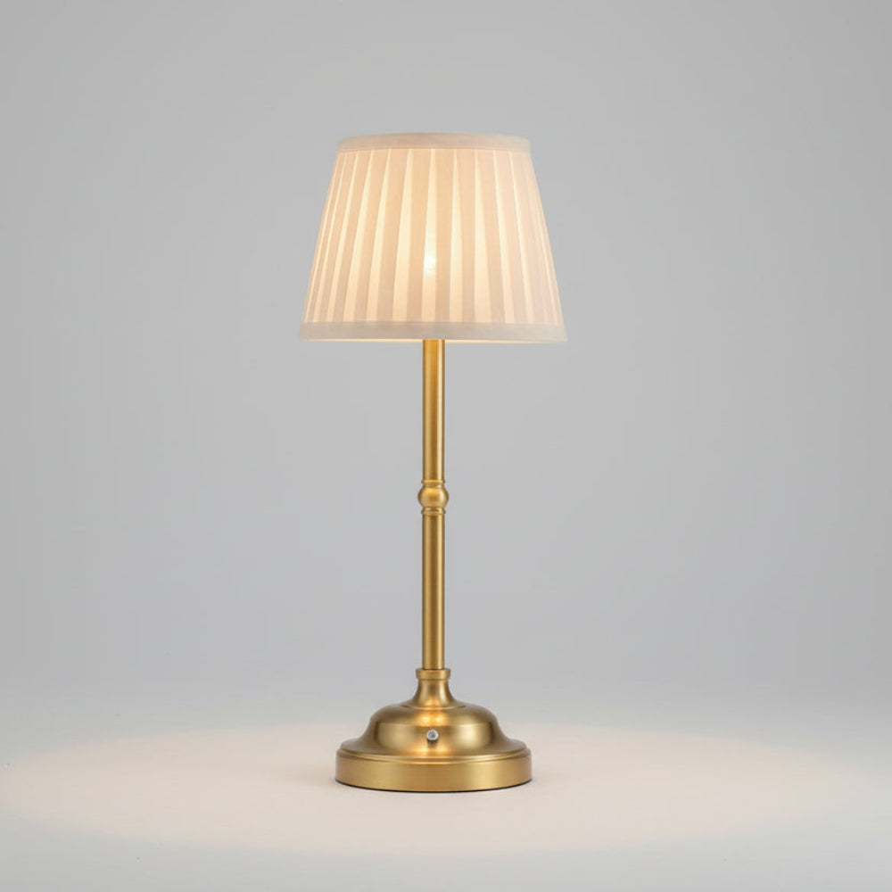 Brass cordless rechargeable table lamp with a pleated fabric shade and touch control base.
