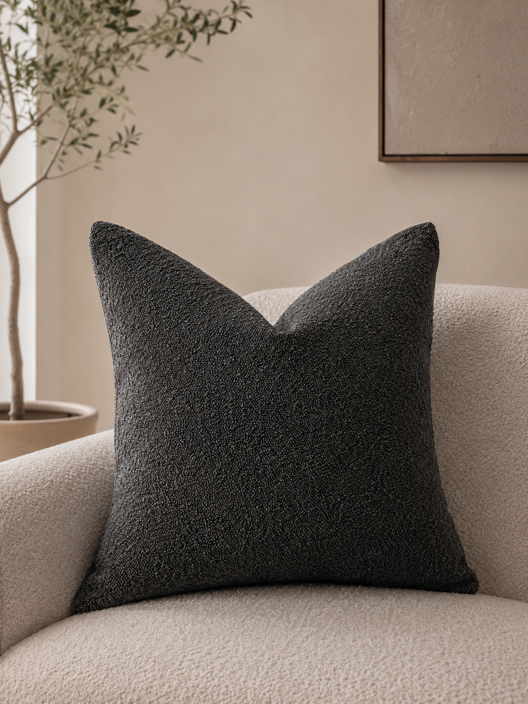 Dark grey textured pillow cover on a cream boucle armchair.