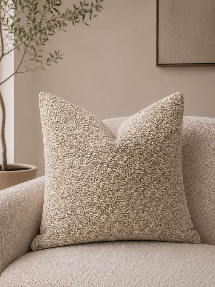 Calen Soft Pillow Cover in a neutral tone with a textured fabric, placed on a matching armchair.
