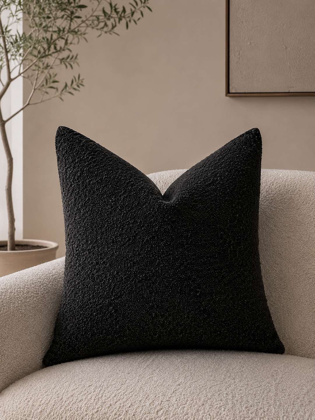 Black textured pillow cover on a cream boucle armchair.