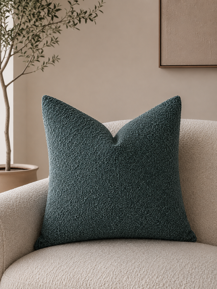 Teal textured pillow cover on a cream boucle armchair.