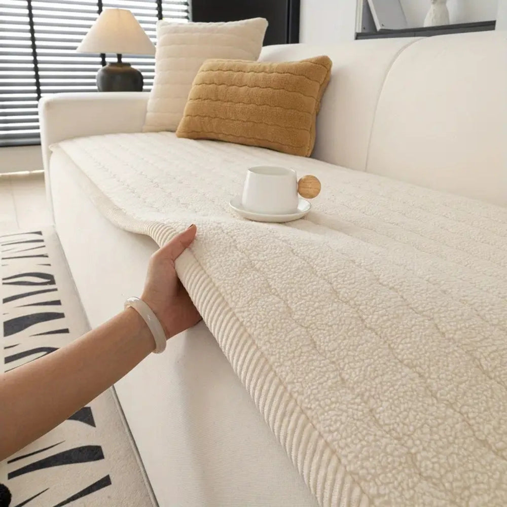 Cream plush sofa cover with a textured pattern, held by a hand.
