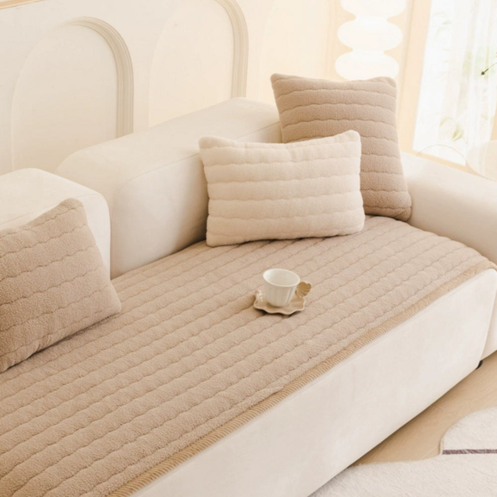 Beige plush sofa cover with textured pillows and a teacup on a saucer.