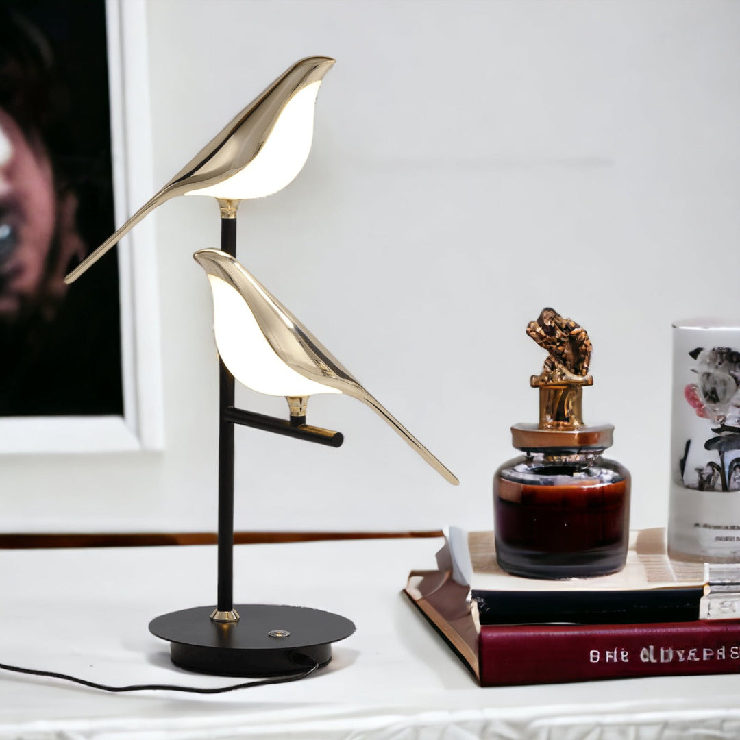Nordic modern desk lamp with two gold bird figures illuminating from within.