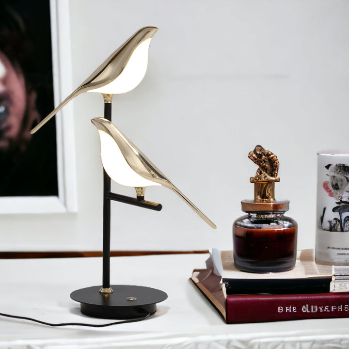 Nordic modern desk lamp with two gold bird figures illuminating from within.