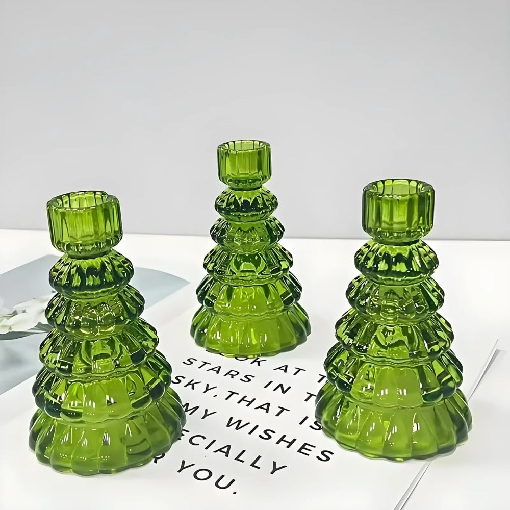 Three green glass Christmas tree-shaped candle holders on a white surface.
